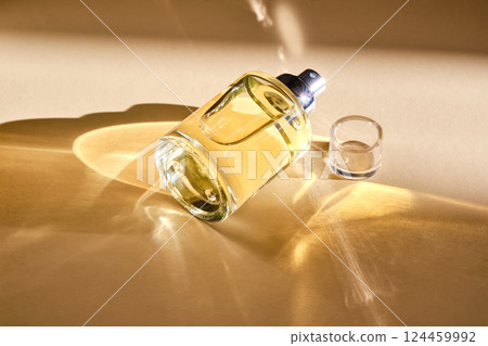 Perfume on a beige background in the rays of bright sun with beautiful highlights. 124459992