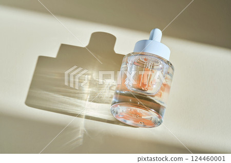 A bottle of luxury serum with petals on a beige background. A bottle of luxury serum with petals on a beige background. 124460001