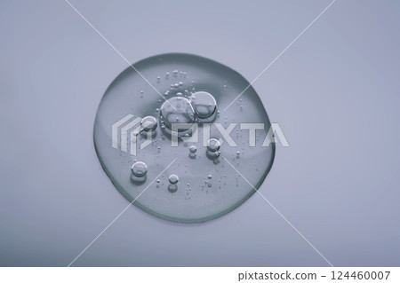 Textured round drop of serum with bubbles on dark blue background. Textured round drop of serum with bubbles on dark blue background. 124460007