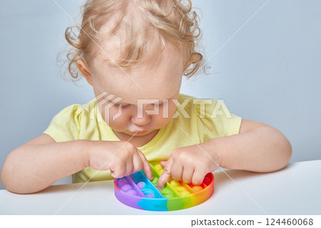 A curly-haired child grabs an anti-stress toy in the ass. Education of children with the help of popular games. A curly-haired child grabs an anti-stress toy in the ass. Education of children with the help of popular games. 124460068