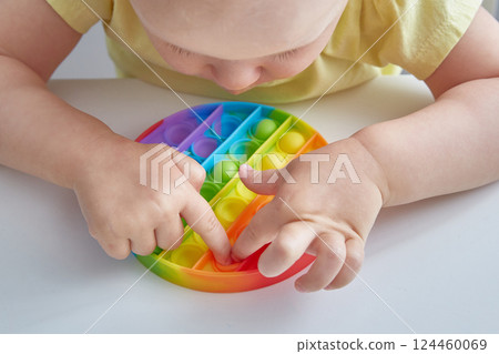 Anti stress toy Pop It. Close up Child Playing With The Pop It Fidget Toy. Happy childhood, popular educational games. Anti stress toy Pop It. Close up Child Playing With The Pop It Fidget Toy. Happy childhood, popular educational games. 124460069
