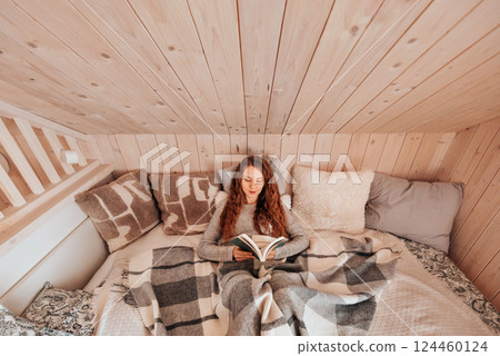 Woman Reading Book in Bed at Cozy Log Cabin Woman Reading Book in Bed at Cozy Log Cabin 124460124