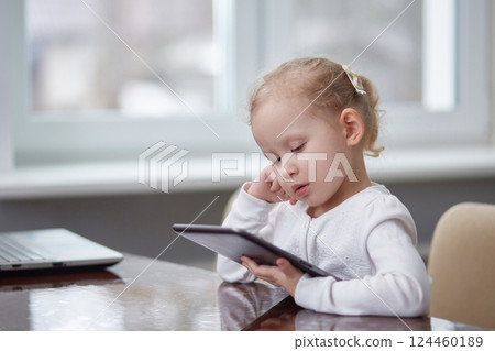 Child with a tablet at the table. Copy space. 124460189