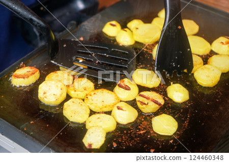 Potatoes cut to small circles, seasoned with spices, grilled on electric grill 124460348