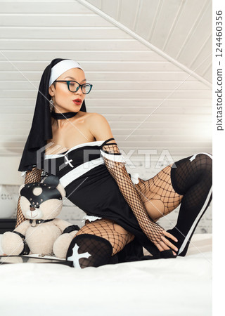 A girl in a sexy nun dress from an adult role-playing sex shop and stockings excitingly poses on a bedroom bed A girl in a sexy nun dress from an adult role-playing sex shop and stockings excitingly poses on a bedroom bed 124460356
