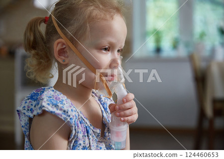 Sick little girl making inhalation with nebulizer to reduce coughing. Bronchitis and asthma treatments for children. 124460653