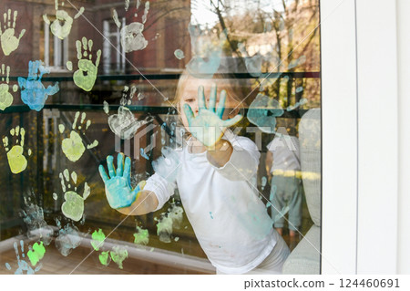 Girl paints with palms on the window. Quarantine Girl paints with palms on the window. Quarantine 124460691