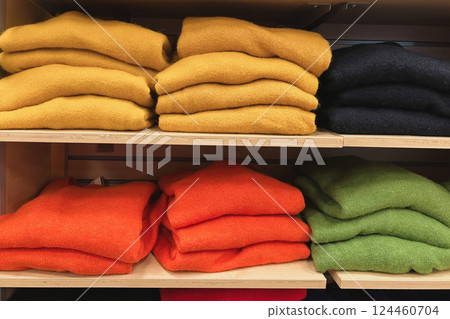 A row of folded sweaters on a shelf in a store 124460704
