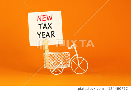 New tax year symbol. Concept words New tax year on beautiful white paper on clothespin. Beautiful orange background. Miniature white bicycle. Business new tax year concept. Copy space. 124460712