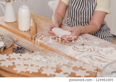 Senior woman cooking in kitchen, hands close up. Older mature lady grandmother hands knead dough bake cookies. Old grandma cook homemade food. Household housewife housework concept 124461005