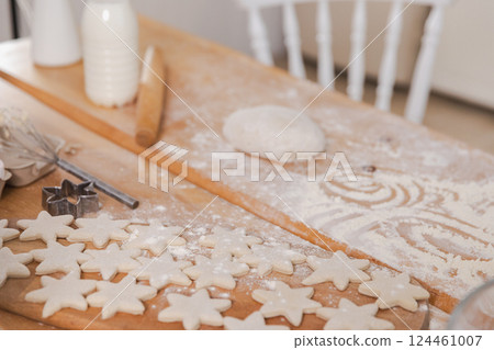 Star shaped raw cookies ready to bake. Baking sheet uncooked biscuits homemade cakes and ingredients on kitchen table. Homemade food preparing process. Household housewife housework concept Star shaped raw cookies ready to bake. Baking sheet uncooked biscuits homemade cakes and ingredients on kitchen table. Homemade food preparing process. Household housewife housework concept 124461007