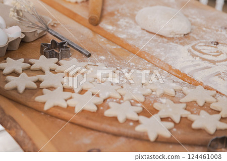 Star shaped raw cookies ready to bake. Baking sheet uncooked biscuits homemade cakes and ingredients on kitchen table. Homemade food preparing process. Household housewife housework concept 124461008