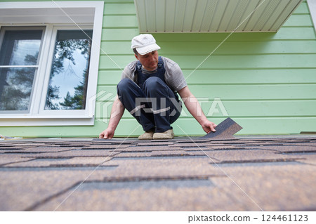 A worker lays soft tiles on the roof of the terrace A worker lays soft tiles on the roof of the terrace 124461123