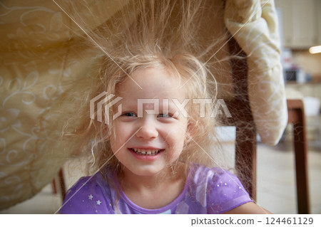 Static electricity electrified the hair of a little girl sitting under a synthetic blanket. Static electricity electrified the hair of a little girl sitting under a synthetic blanket. 124461129