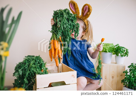 Cute little child girl wearing bunny ears holding fresh bunch of carrots Cute little child girl wearing bunny ears holding fresh bunch of carrots 124461171