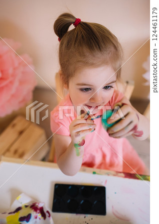 Cute girl painting Easter eggs in bright colourful room 124461179