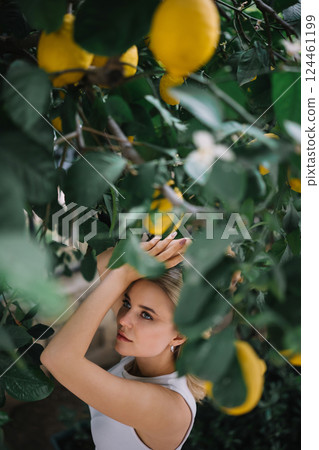 Outdoor portrait of beautiful young woman posing near lemon tree 124461199