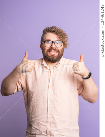 Crazy funny man showing double thumbs up on purple background. Positivity, humor and enthusiastic support through expressive body language. Crazy funny man showing double thumbs up on purple background. Positivity, humor and enthusiastic support through expressive body language. 124461248