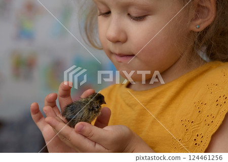 A girl is playing with a small bird pet. Friendship of animals and people. 124461256