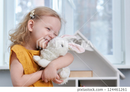 Smiling girl hugs a white rabbit toy. The concept of reconciliation and love. Copy Space 124461261