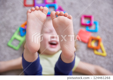 Close-up of the legs of a child laughing on the carpet 124461268