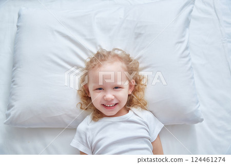 Smiling cute girl on a white pillow. Copy space 124461274