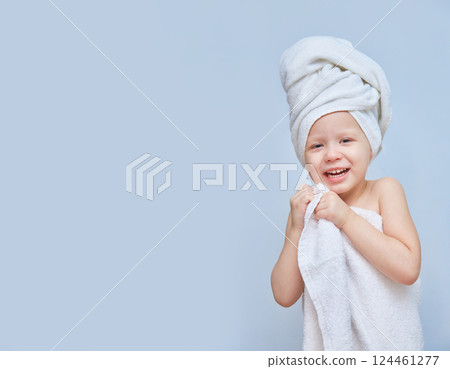 Laughing girl dressed in a white towel. Spa day in a beauty salon. Towel on the head. Daughter at the Spa. Beauty salon concept. beautiful face. Happy child. Copy space or space for a product. 124461277