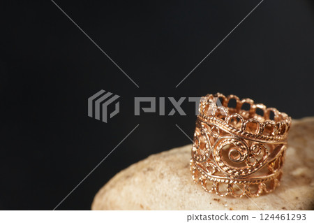 A gold ring on a stone. Black background with copy space. 124461293