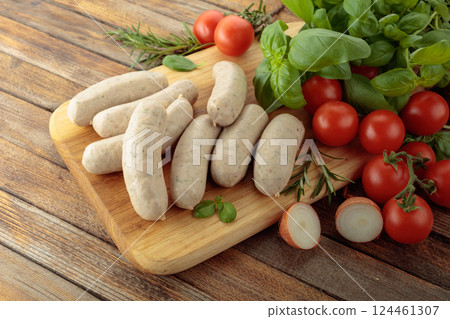 Bavarian white sausages with basil and tomatoes on a cutting board. Bavarian white sausages with basil and tomatoes on a cutting board. 124461307