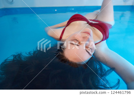 Portrait of a relaxed young woman swimming in the salt water of the pool. Floating concept. 124461796