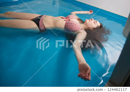 Wellness - young woman floating in Spa or swimming pool, she is very relaxed. Copy spase. 124462117