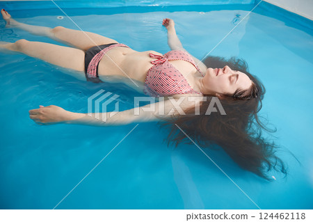 Wellness - young woman floating in Spa or swimming pool, she is very relaxed. 124462118
