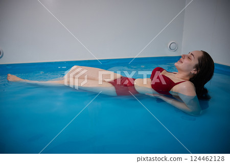 A young woman in a room with sea water in a bathtub. Relaxation therapy and relaxation. Copy Space. A young woman in a room with sea water in a bathtub. Relaxation therapy and relaxation. Copy Space. 124462128