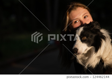 Young Caucasian woman hugging her border collie dog while walking in the park.  124462144