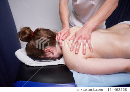 Body massage procedure. A woman in a spa salon. The masseur is working on her back 124462268