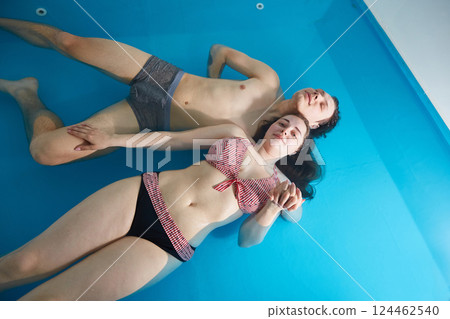 Couple in love swims in the pool. Wellness and spa therapy for two. Copy space. 124462540