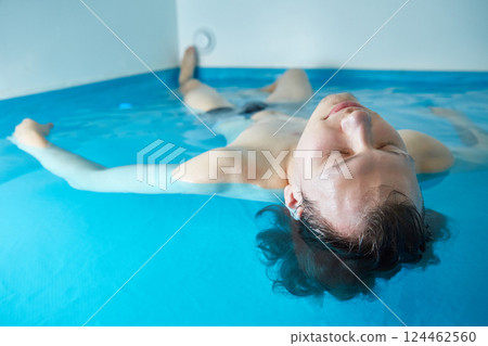 Man is swimming in the pool on his back. Wellness, relaxation and spa therapy. Man is swimming in the pool on his back. Wellness, relaxation and spa therapy. 124462560