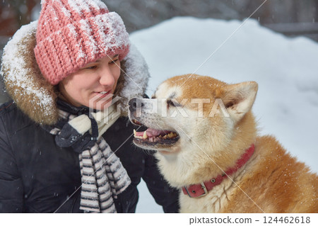 A woman in a snowy winter with an akita dog. Close-up 124462618