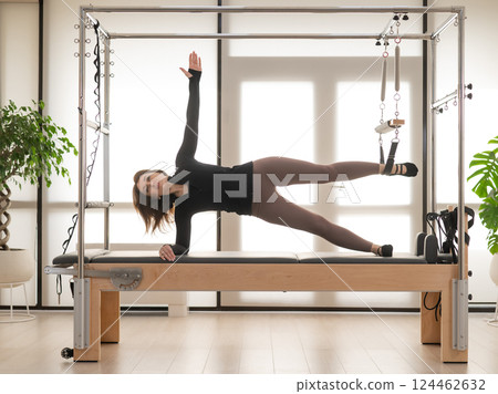 Woman doing Pilates on reformer. 124462632