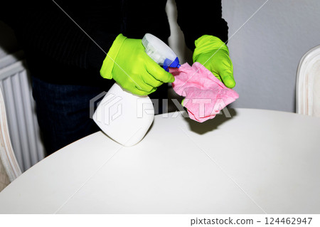 A man wearing cleaning gloves wipes the dining table. 124462947