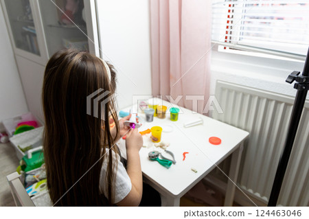 Little girl with long brown hair playing with plasticine Little girl with long brown hair playing with plasticine 124463046