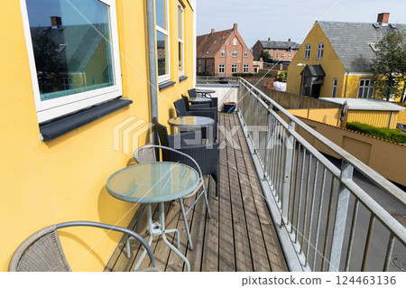 A large veranda or balcony with chairs and tables for relaxing on a summer day. 124463136