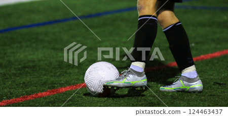 Soccer Player Dribbling a Ball on a Brightly Lit Field During Evening Soccer Player Dribbling a Ball on a Brightly Lit Field During Evening 124463437