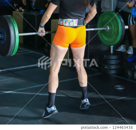 Weightlifting Competition With Focused Female Athlete in Bright Orange Shorts Weightlifting Competition With Focused Female Athlete in Bright Orange Shorts 124463438