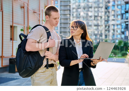 Female teacher talking with teenager student guy, outdoor, college building background Female teacher talking with teenager student guy, outdoor, college building background 124463926