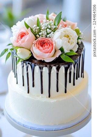 Elegant floral cake with chocolate ganache and pastel roses displayed at an intimate event 124464306