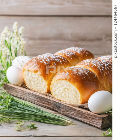 Traditional Easter bread and decorated eggs presented on a rustic wooden table adorned with spring greenery. Generative AI 124464667