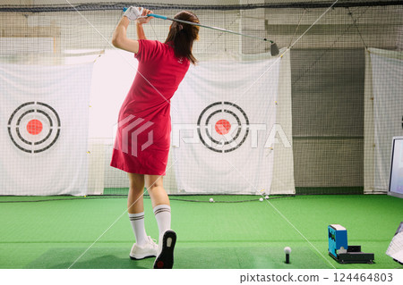 一名女子在室內高爾夫練習場練習 124464803