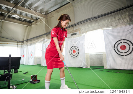 一名女子在室內高爾夫練習場練習 一名女子在室內高爾夫練習場練習 124464814