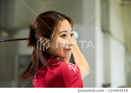 一名女子在室內高爾夫練習場練習 一名女子在室內高爾夫練習場練習 124464819